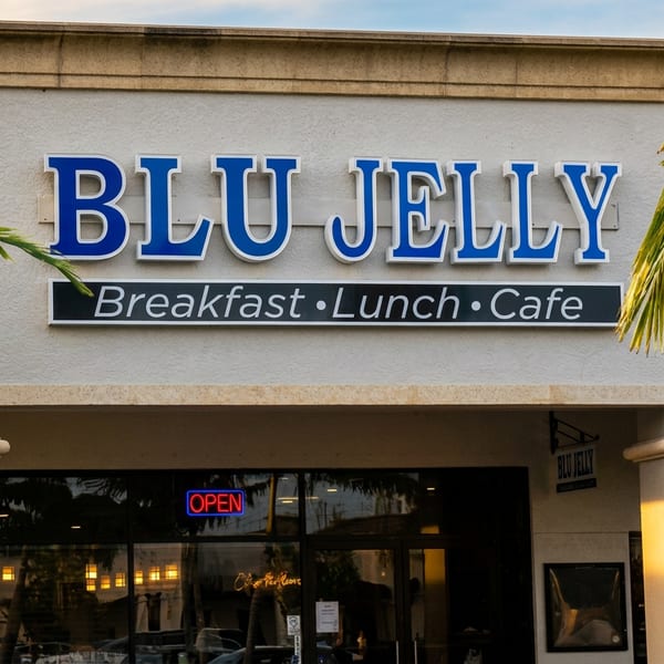 Blu Jelly restaurant exterior with blue sign, 'Breakfast Lunch Cafe,' and palm trees.