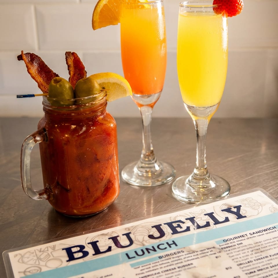 Bloody Mary, two mimosas, and a Blu Jelly lunch menu on a metallic counter.